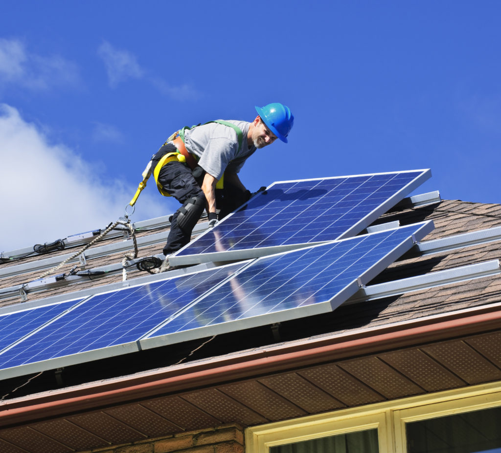 man installing solar panels onto a roof